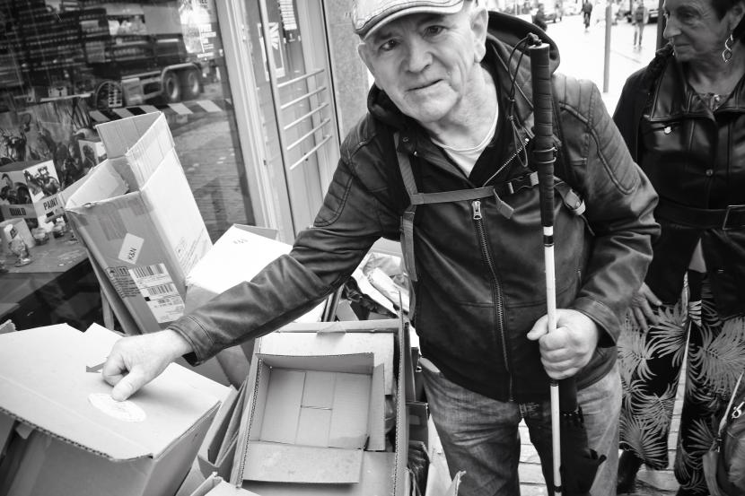 Vrijwilliger Dirk kleeft een Team Trottoir-sticker op een stapel kartonnen dozen op de stoep.