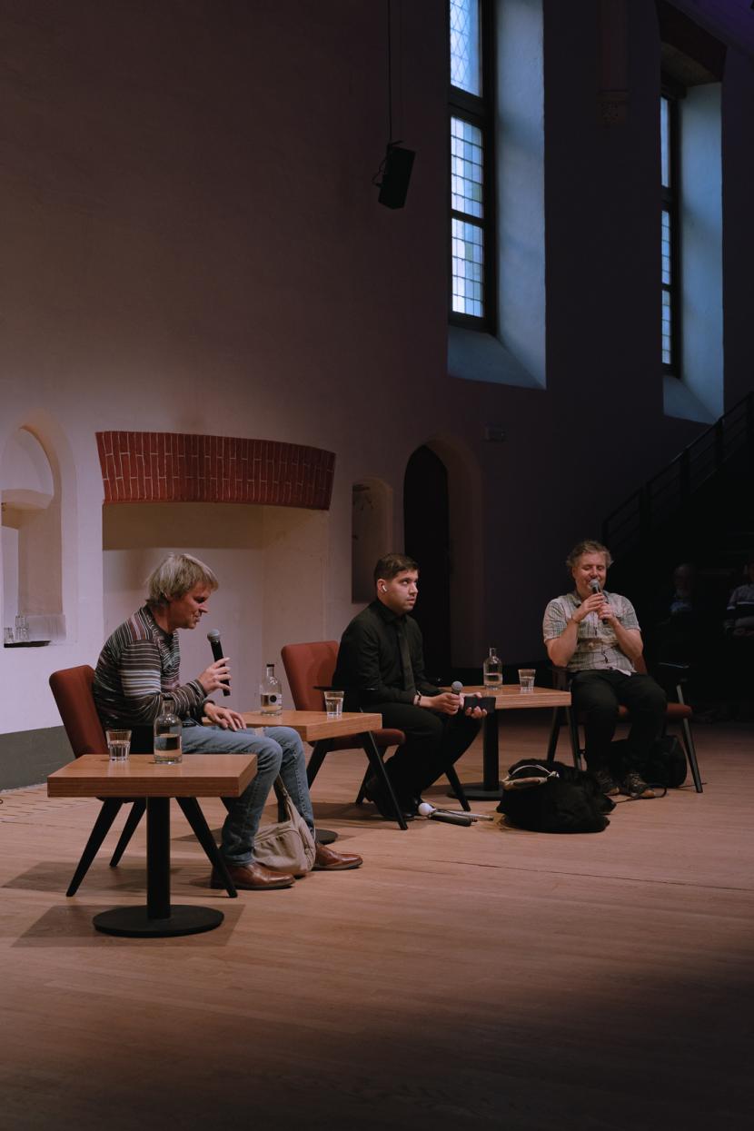 Vooraan naast elkaar zitten Sacha Van Loo, Youssri Mejdoubi en Harry Viaene.