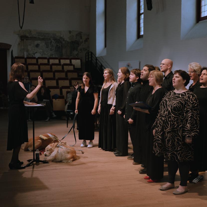 Lucy Kloeck dirigeert het ICC Choir. De koorleden zingen het publiek toe.